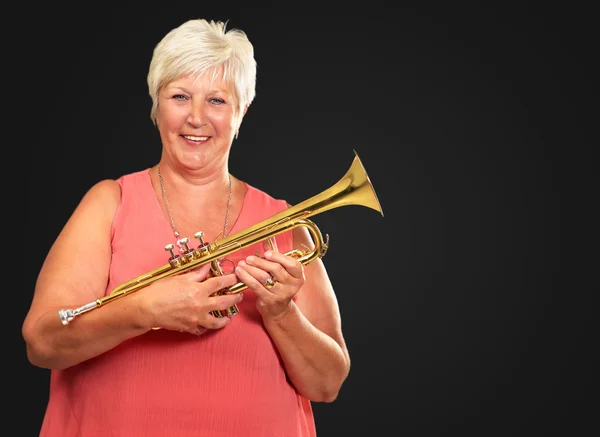 Kypsä nainen puhaltaa hänen trumpetti — kuvapankkivalokuva