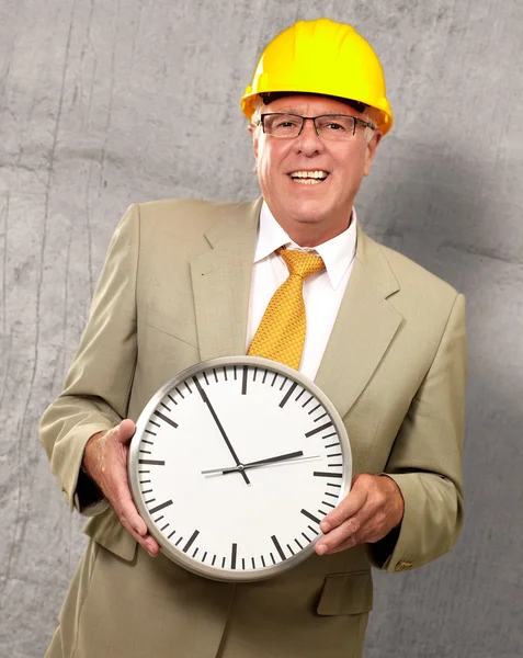 Portret van een senior man houden een muur horloge — Stockfoto