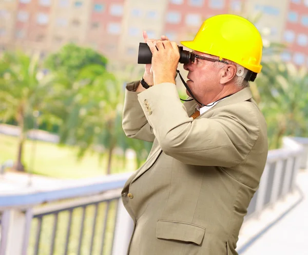 Arquiteto sênior olhando através de binóculos — Fotografia de Stock