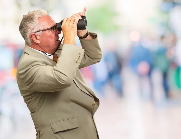 Starszy mężczyzna patrzący przez lornetkę — Zdjęcie stockowe