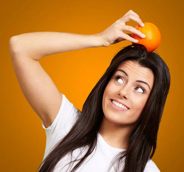 Ritratto di giovane donna che tiene arancione sulla testa sopra l'arancio — Foto Stock