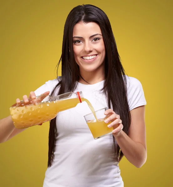 Porträt einer jungen Frau, die einen Orangensaft in ein Glas gießt — Stockfoto