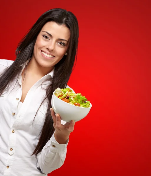 Портрет молодой женщины, держащей салат над красным — стоковое фото