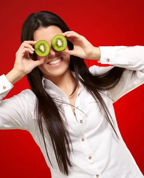 Portrait of young girl holding kiwi slices in front of her eyes — Stock Photo, Image