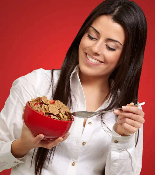 Portret van gezonde jonge vrouw eten granen over rood — Stockfoto