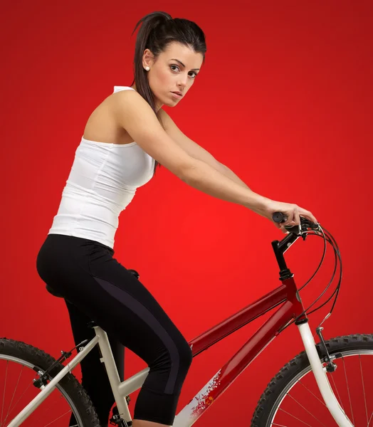 Retrato de mujer joven en bicicleta sobre fondo rojo — Foto de Stock