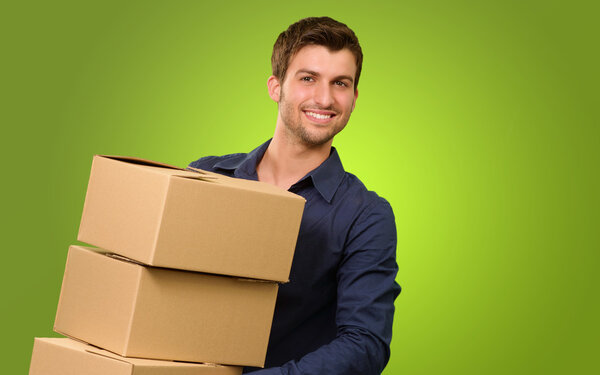 Молодой человек держит стопку картонных коробок
