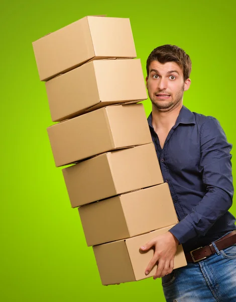 Um jovem segurando uma pilha de caixas de papelão — Fotografia de Stock