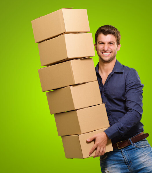 Молодой человек держит стопку картонных коробок
