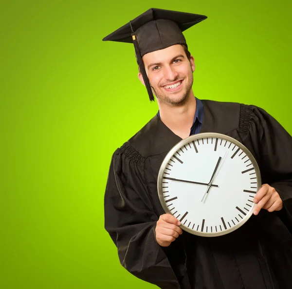 Homme diplômé tenant horloge — Photo