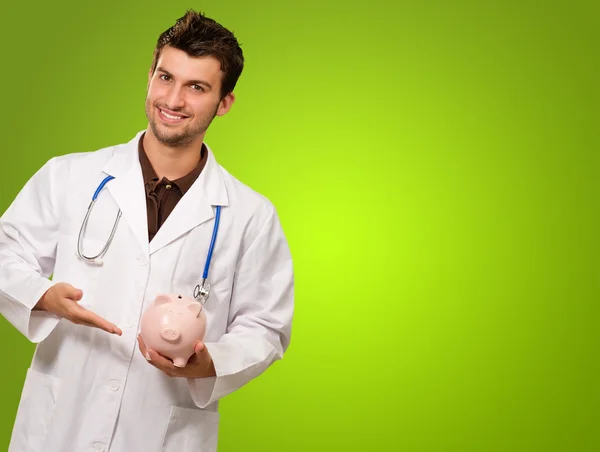 Jovem médico segurando um porquinho banco — Fotografia de Stock