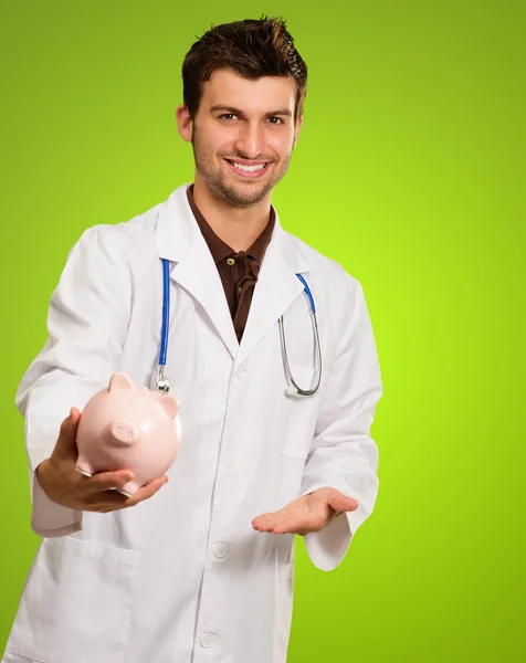 Joven doctor sosteniendo una alcancía — Foto de Stock