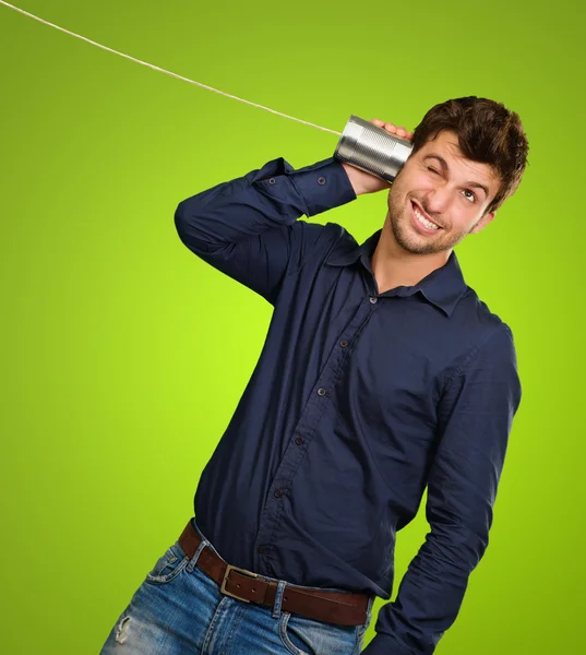 Uomo In ascolto Da Tin Can Telefono su uno sfondo verde — Foto Stock