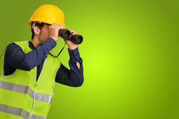 Un joven ingeniero mirando a través de prismáticos — Foto de Stock