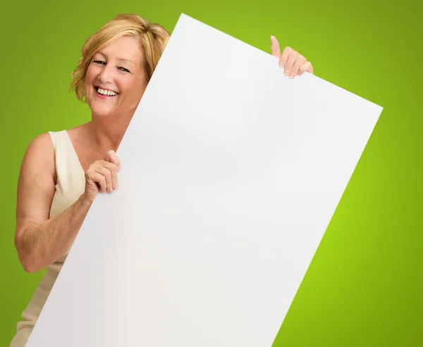 Feliz maduro mulher segurando um branco Billboard — Fotografia de Stock