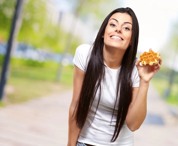 Uma jovem mulher segurando e mostrando no waffle — Fotografia de Stock