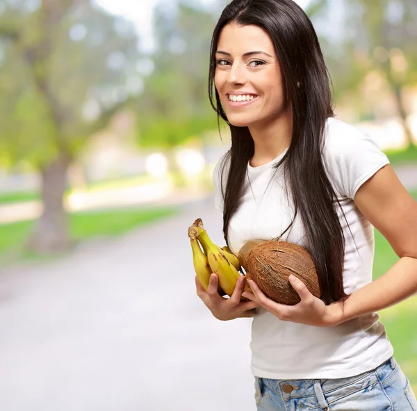 Giovane ragazza in possesso di banana e cocco — Foto Stock