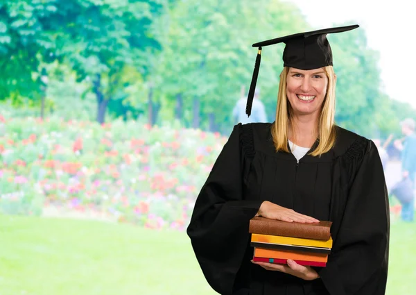 Glad graduate kvinna anläggning böcker — Stockfoto