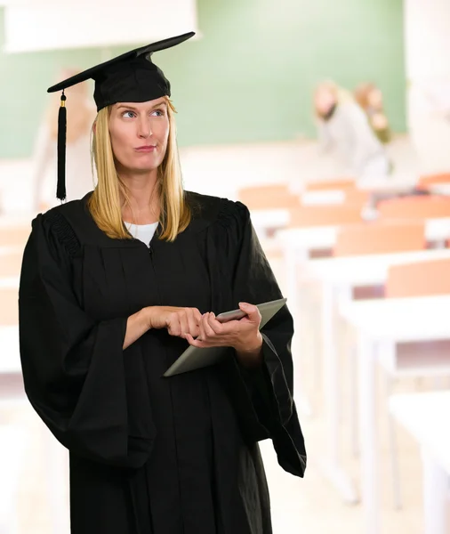 Förvirrad graduate kvinna med digital tablet — Stockfoto