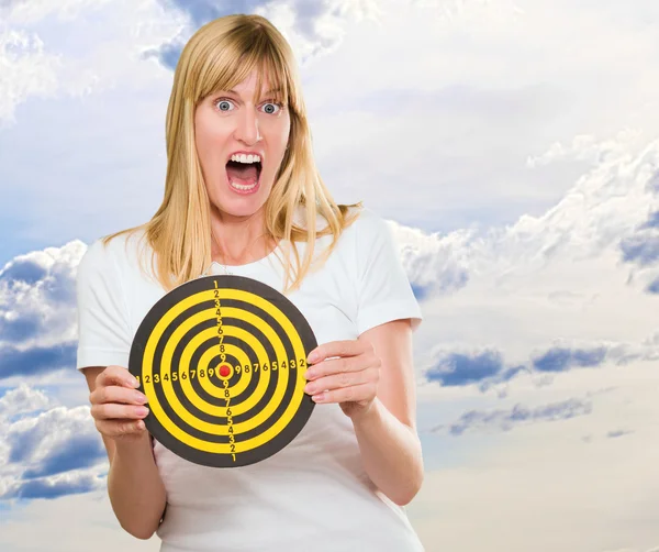 Donna impaurita che tiene Dartboard — Foto Stock