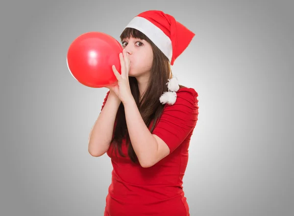Žena na sobě klobouk vánoční a fouká balónek — Stock fotografie