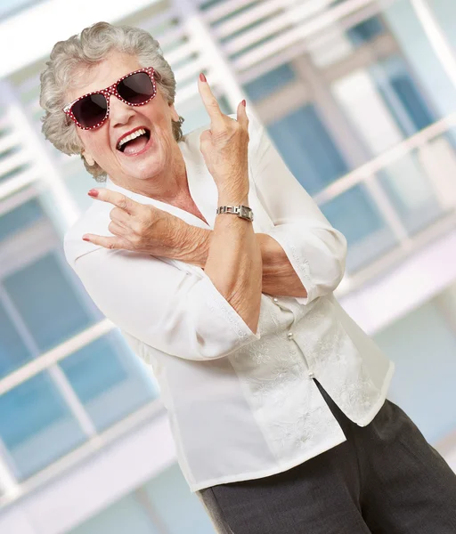 Ανώτερος γυναίκα φοράει γυαλιά ηλίου, κάνει funky δράση — Φωτογραφία Αρχείου