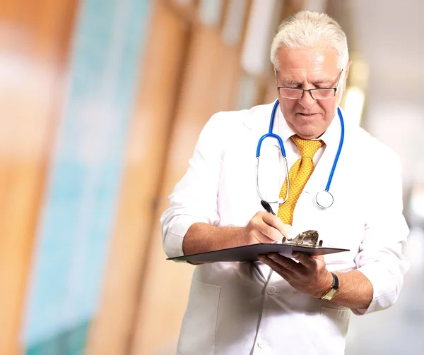 Старший чоловік лікар пише на кишені — стокове фото
