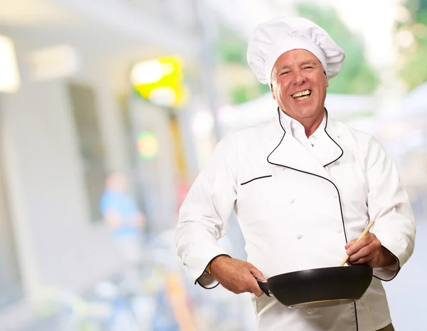 Männlicher Koch rührt eine Antihaftpfanne, Hintergrund — Stockfoto