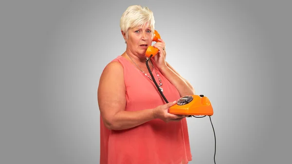 Retrato de una mujer mayor sosteniendo un teléfono retro — Foto de Stock