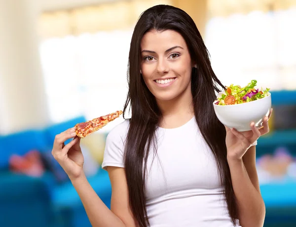 Vrouw houdt een stuk van pizza en salade kom — Stockfoto