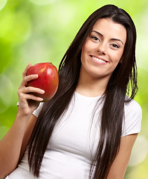 Eine junge Frau hält eine Mango in der Hand — Stockfoto