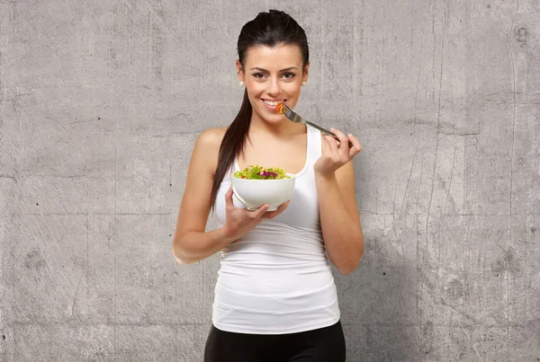 Wanita muda memegang dan makan salad — Stok Foto