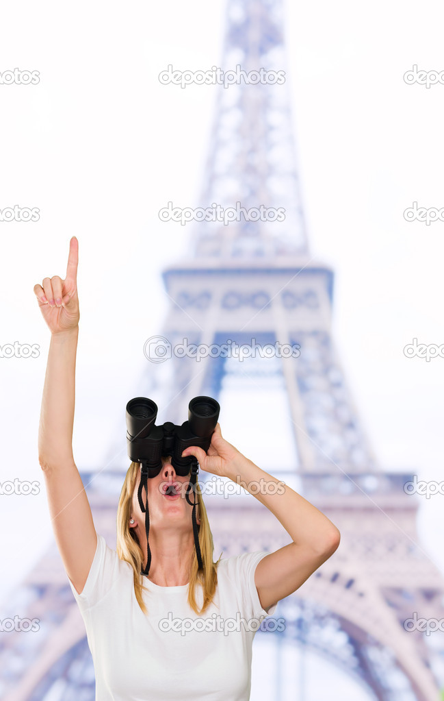 woman looking through binoculars and pointing up