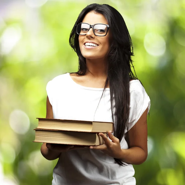 Retrato de una joven sosteniendo libros sobre un fondo natural —  Fotos de Stock