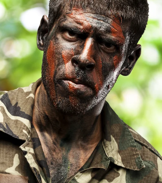 Young soldier with camouflage paint looking very serious over at — Stock Photo, Image