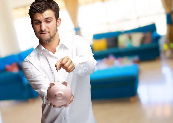 Ein Geschäftsmann steckt eine Münze in ein rosa Sparschwein — Stockfoto