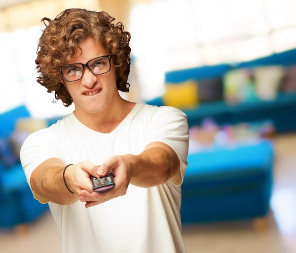 Portrait Of Young Man With Glasses Changing Channel With Tv Cont