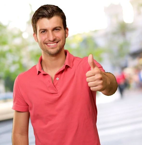 Junger Mann lächelt mit erhobenem Daumen — Stockfoto