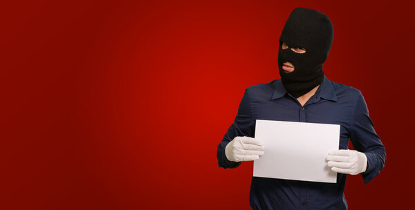 Man wearing a robber mask showing a blank paper