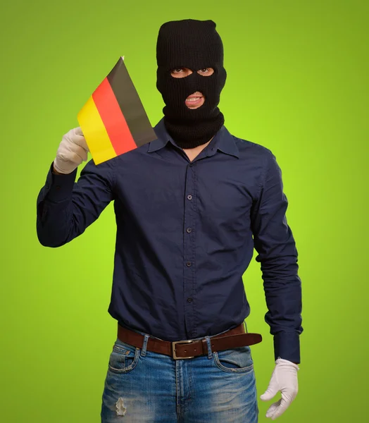Человек в маске грабителя и с флагом в руках — стоковое фото