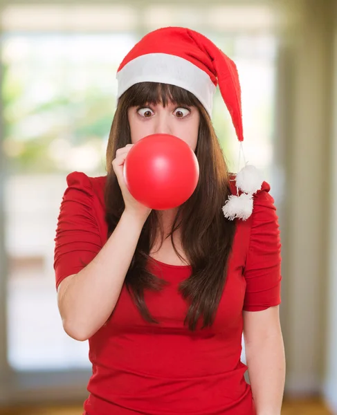 Рождественская женщина, надувающая воздушный шар с скрещенными глазами — стоковое фото