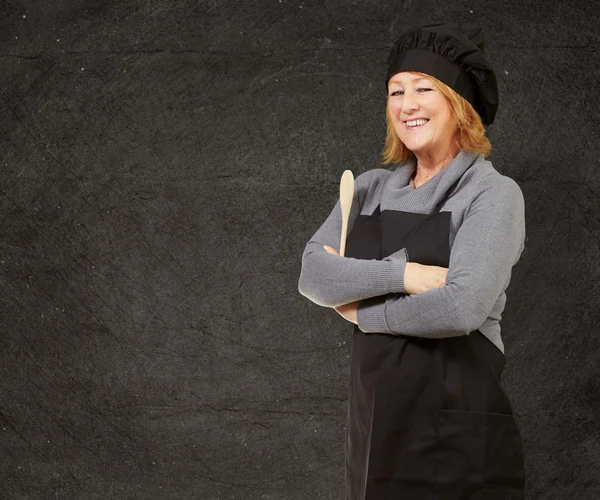 Retrato de la mujer cocinera usando delantal contra una pared grunge —  Fotos de Stock
