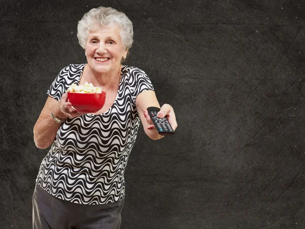Портрет счастливой пожилой женщины, смотрящей телевизор на фоне ухмылки — стоковое фото