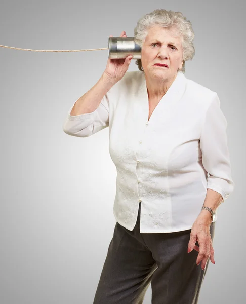 Retrato de uma mulher idosa ouvindo com estanho de metal — Fotografia de Stock