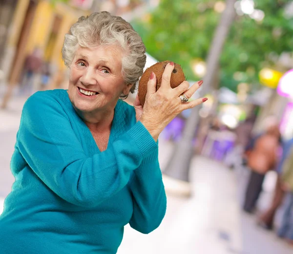 Senior happy woman holding coconut — Stock Photo, Image