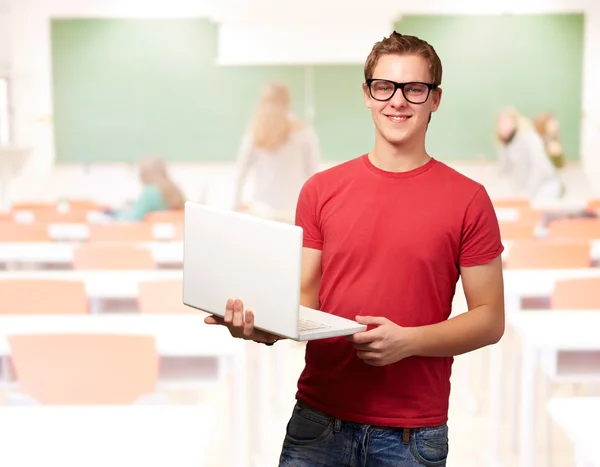 Portrait of young student man holding laptop in classroom — Stock Photo, Image