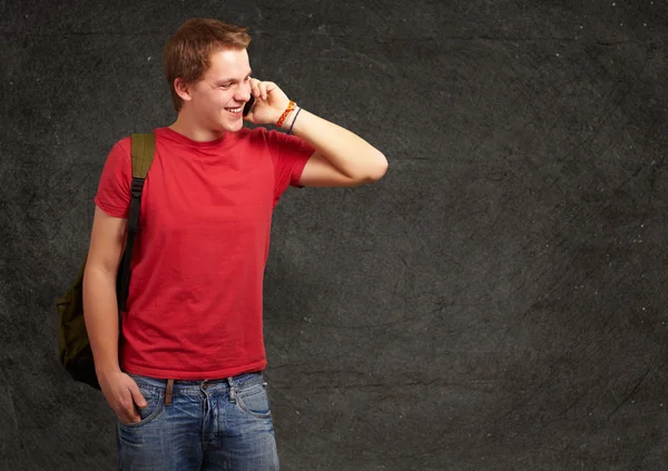 Portrait of young man talking on mobile against a grunge wall — Stock Photo, Image