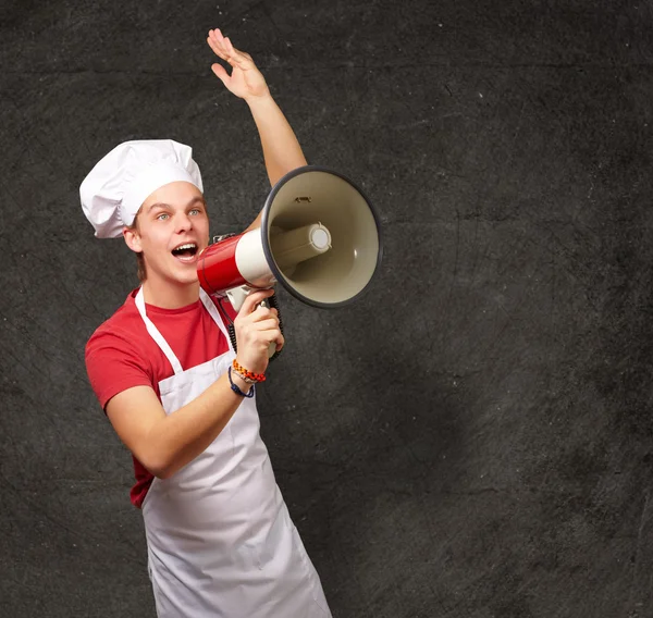 Retrato de jovem cozinheiro gritando com megafone contra um gru — Fotografia de Stock