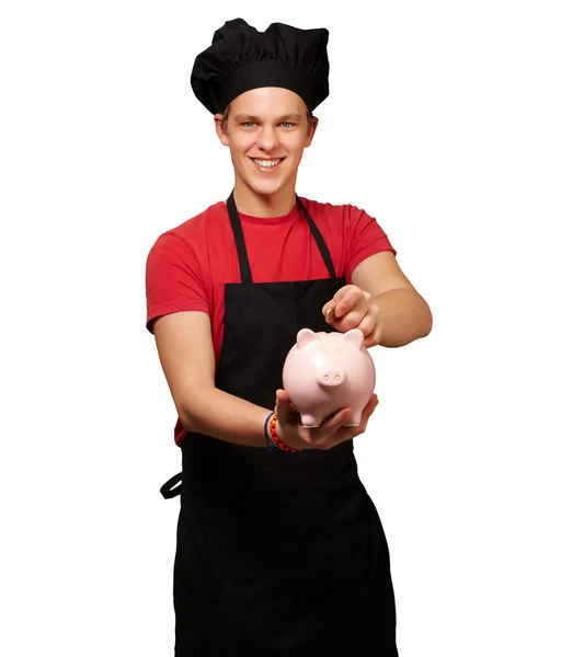 Male chef holding a piggybank and a coin — Stock Photo, Image