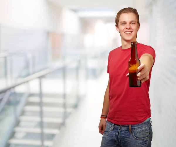 Retrato de jovem segurando cerveja na entrada do buildin moderno — Fotografia de Stock